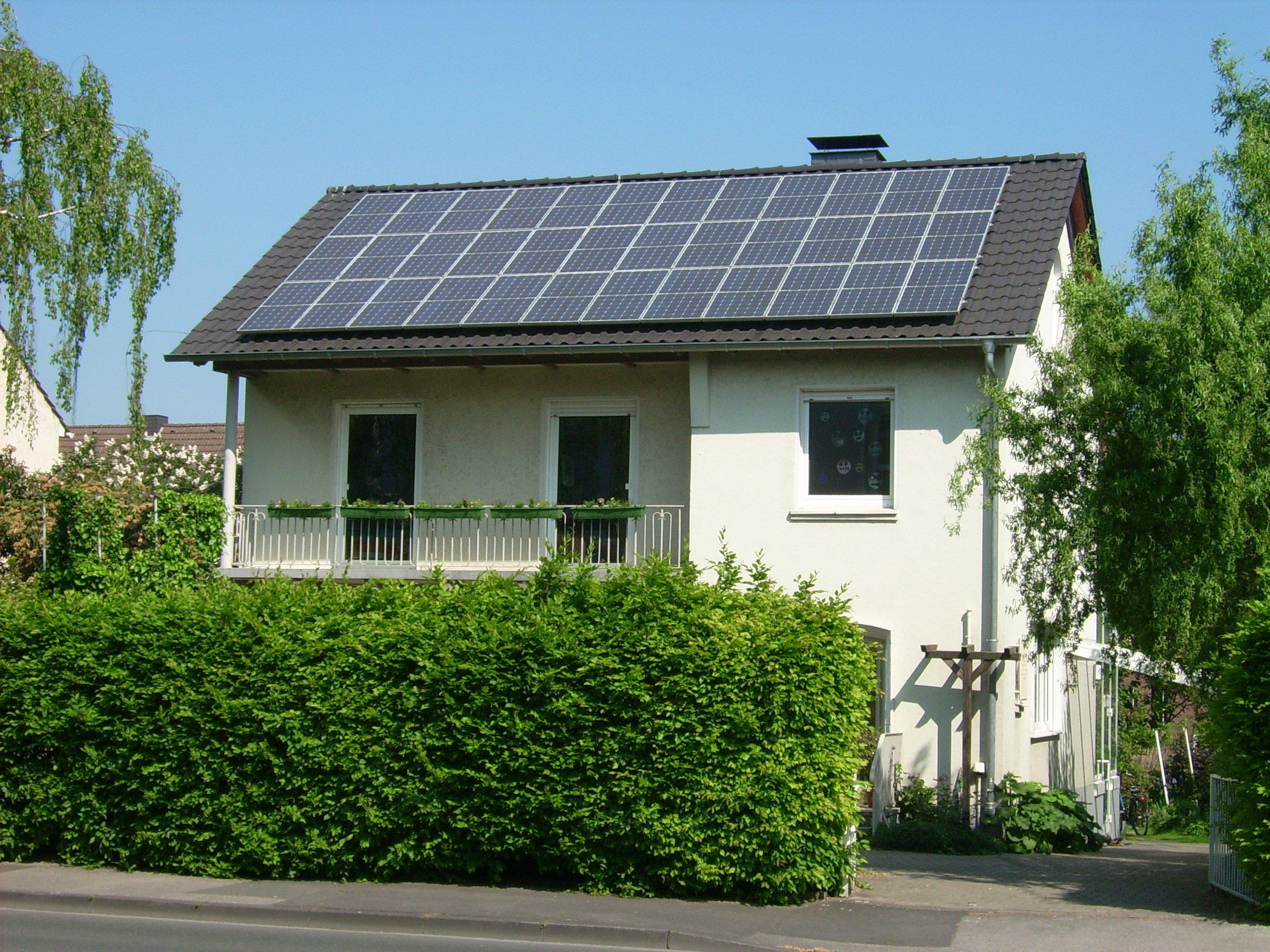 Ein Einfamilienhaus im Grünen mit Solarpanelen auf dem Dach.